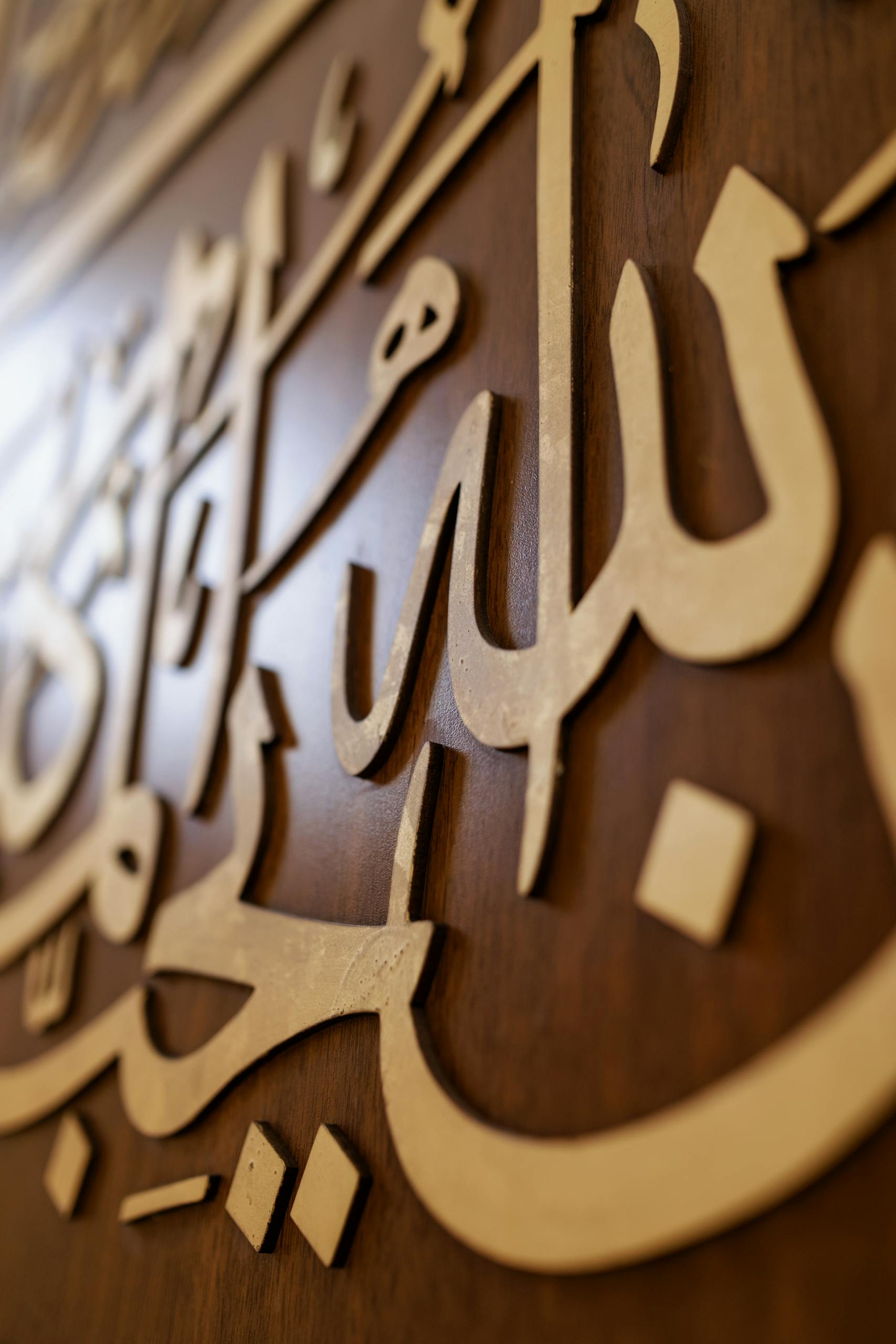 Close-up of ornate Arabic calligraphy on a wooden wall, highlighting Islamic artistry.